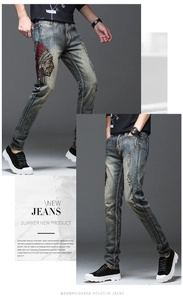 Détail d'un jean bleu clair usé avec broderie colorée de chef amérindien sur la jambe