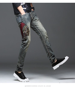Détail de la broderie indienne et des trous tendance sur le jean bleu ajusté pour homme