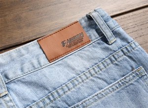 Détail macro du patch en cuir marron et des coutures sur un jean denim bleu clair