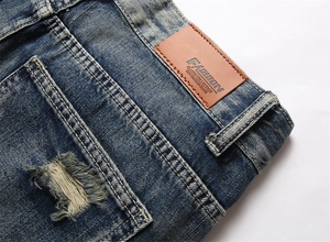Detail einer blau gewaschenen Jeans mit braunem Lederpatch und Distressed-Textur am Bund