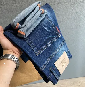 Detailaufnahme der dunkelblauen Jeans mit Leder-Markenpatch und hochwertigen orangen Nähten