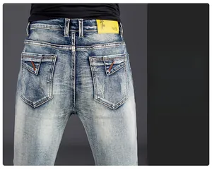 Detail of slim fit men's jeans featuring faded wash, back pockets, and leather waist patch