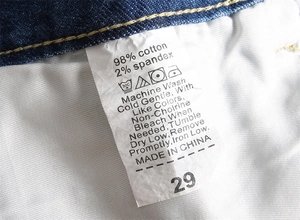 Gros plan de l'étiquette d'entretien du jean indiquant 98% coton et conseils de lavage