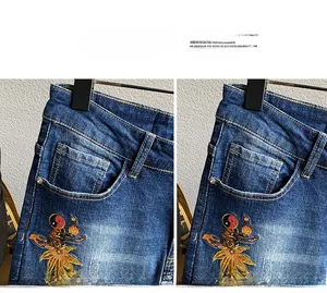Nahaufnahme der feinen Stickerei und der verwaschenen Denim-Textur dieser blauen Herrenjeans