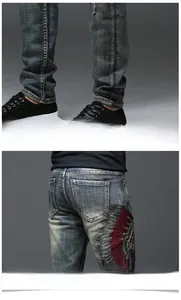 Détail de broderie ethnique de plumes sur un jean en denim délavé bleu marine pour homme