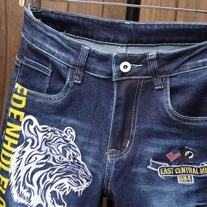Streetwear dark blue jeans featuring white tiger embroidery and yellow graphic side print