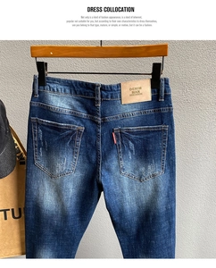 Detail von blauer Jeans mit Leder-Patch und Stickerei an einem Holz-Kleiderbügel