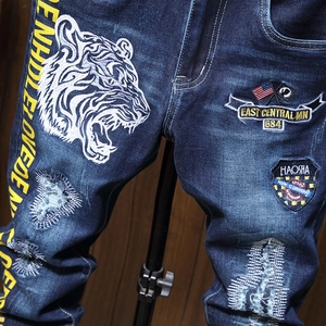 Distressed blue denim straight jeans with tiger embroidery and letter patches