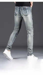 Detail of light blue slim fit men's jeans with orange stitching and back pocket patches