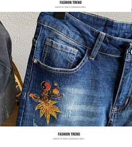 Detail einer dunkelblauen Jeans mit aufwendiger Yin-Yang-Stickerei an der Vordertasche