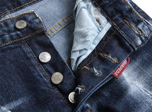 Vue détaillée macro d'un jean en denim délavé avec une braguette à boutons métalliques gris