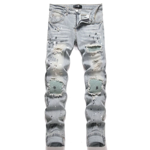 Slim fit distressed blue denim jeans with paint splatters and ribbed patch details