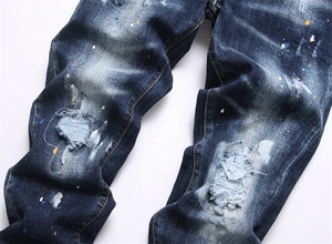 Gros plan d'un jean bleu délavé avec des taches de peinture et des détails usés