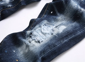 Vue détaillée du jean denim bleu avec des éclaboussures de peinture et des patchs cousus main