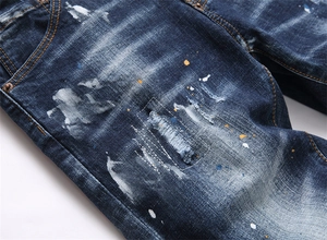 Détail macro d'un jean bleu foncé avec taches de peinture et empiècements délavés