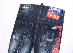 Détail de jean denim bleu usé avec taches de peinture et lettrage de marque iconique