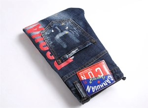 Détail du jean punk bleu montrant le logo DSQUARED2 rouge et des éclats de peinture
