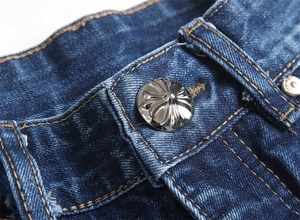 Dettaglio della vita in denim con bottone a croce in argento e cuciture a contrasto