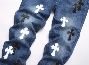 Dettaglio del ricamo con toppe a croce su jeans blu lavato a gamba dritta