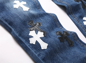 Dettaglio delle toppe in pelle a croce e cuciture su jeans blu dal taglio sottile