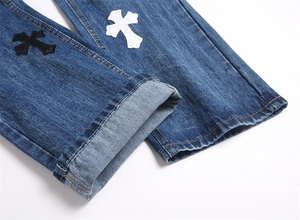 Dettaglio dei jeans punk blu con toppe a croce in similpelle e cuciture di alta precisione
