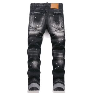 Detail view of charcoal slim jeans with distressed white paint splashes and leather patch