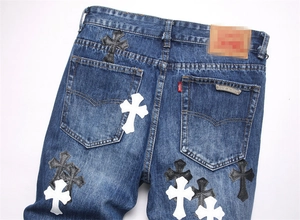 Dettaglio di toppe a croce in pelle e badge logo in metallo su jeans blu punk slim fit