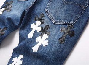 Dettaglio delle toppe a croce e cuciture a contrasto su jeans in denim blu scuro