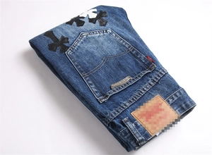 Vista dettagliata dei jeans lavaggio blu scuro con patchwork di croci in pelle e placca metallica