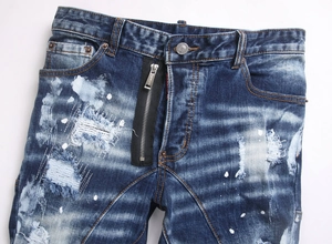 Close-up of distressed denim with white paint splatters and decorative zipper detail