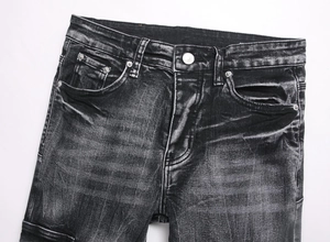 Close-up of washed black slim flare jeans featuring metal button and whiskering texture