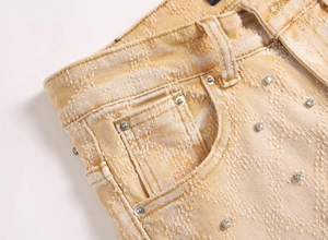 Detailaufnahme der schwer gewaschenen senfgelben Slim-Jeans mit Metallnietenbesatz