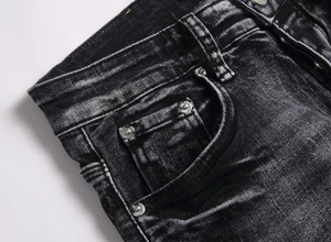 Macro detail of black washed denim jeans showing waistband pocket and metal rivets