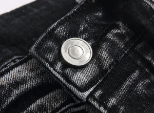 Close-up of a silver metal button on black washed slim fit flare jeans for men