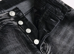 Close-up of four matte silver buttons on a black washed denim fly with quality stitching