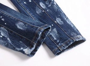Detailed macro view of white paint splatter and distressed frayed hem on denim jeans
