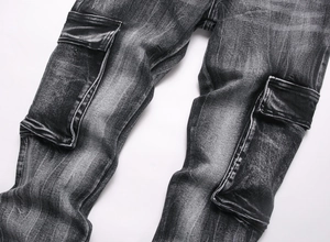 Detail of washed black denim cargo pants with side flap pockets and distressed finish