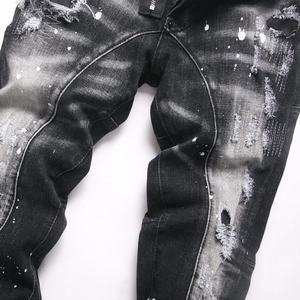Distressed black slim fit men's jeans with heavy wash ripped holes and white paint splatters