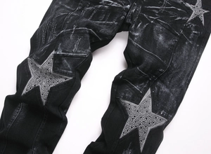 Close-up of black washed slim denim jeans with large rhinestone star patch detail