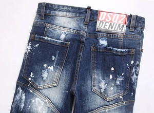 Detail of distressed dark blue jeans with white paint splatter and leather waist tag