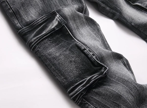 Detail of cargo flap pocket on black washed denim jeans with heavy stitching