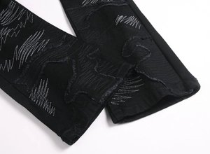 Gros plan de l'ourlet évasé en denim noir avec broderie blanche et bords effilochés