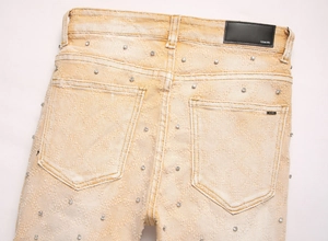 Details der gelben Slim Fit Flare Jeans mit funkelnden Strasssteinen und schwarzem Lederpatch