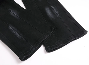 Detail view of washed black denim hem with vintage fading and precise stitching on jeans