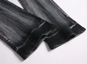 Detailed macro view of retro washed hem and stitching on black flared jeans for men