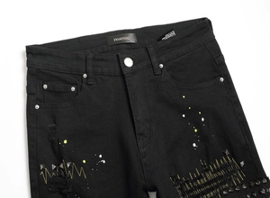 Detail of black distressed jeans with yellow lightning embroidery and metal pyramid studs