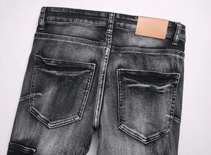 Detail view of washed black slim flare jeans with back pockets and leather patch