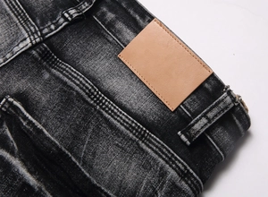 Detail of waist area showing brown leather patch and stitching on black flared jeans