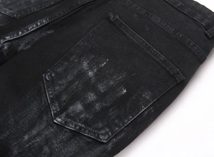 Macro shot of black denim jeans rear pocket with heavy washed texture and stitch detail