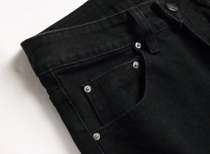 Detaillierte Nahaufnahme von schwarzem Denim-Stoff mit Silbernieten und verstärkten Nähten